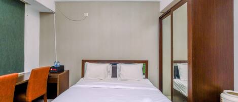 Una habitación de hotel con una cama, un escritorio, una silla y un espejo.