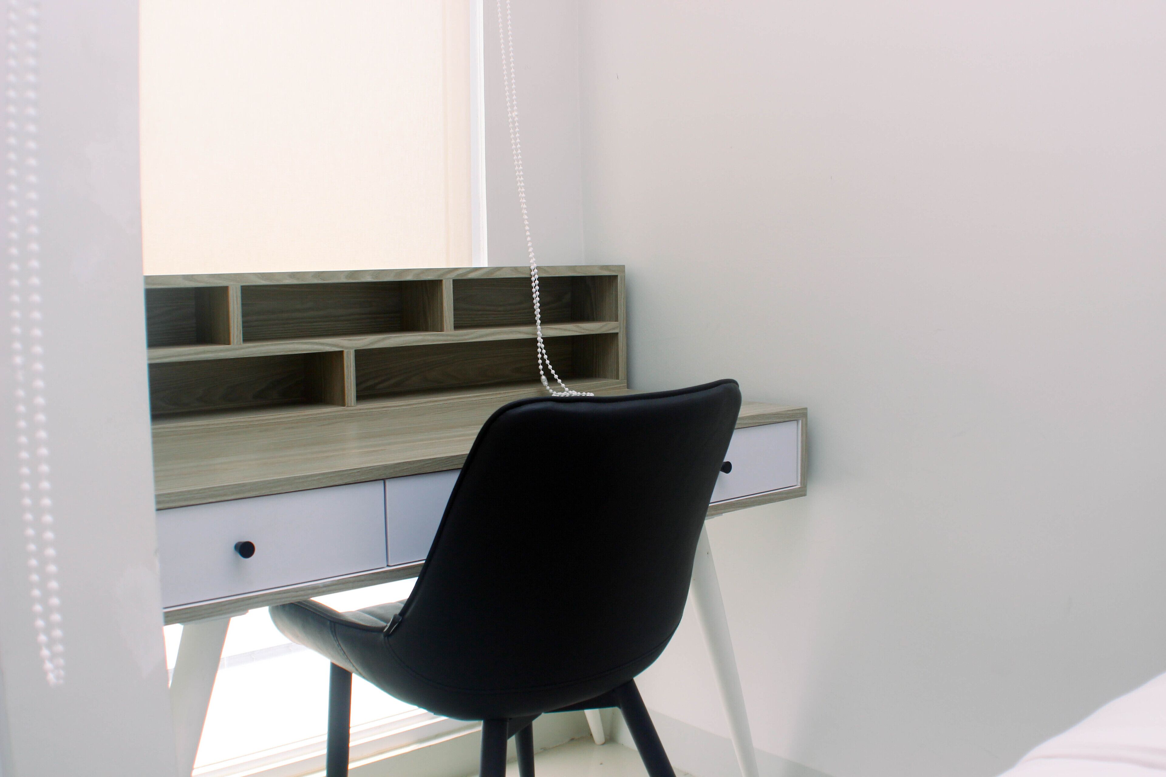 A modern room with a desk, a chair, and a window.