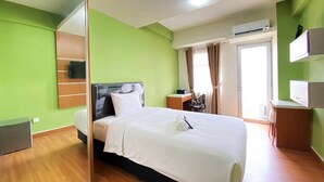 Une chambre d’hôtel équipée d’un lit, d’un bureau, d’une chaise, d’un climatiseur et d’un miroir.