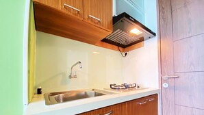 Une cuisine de taille réduite, équipée d’un évier, d’une cuisinière et de meubles de rangement en bois.
