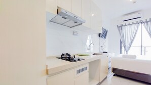 Una cocina moderna con estufa a gas, microondas y horno empotrado. Hay una ventana con cortinas y un aire acondicionado en la pared.