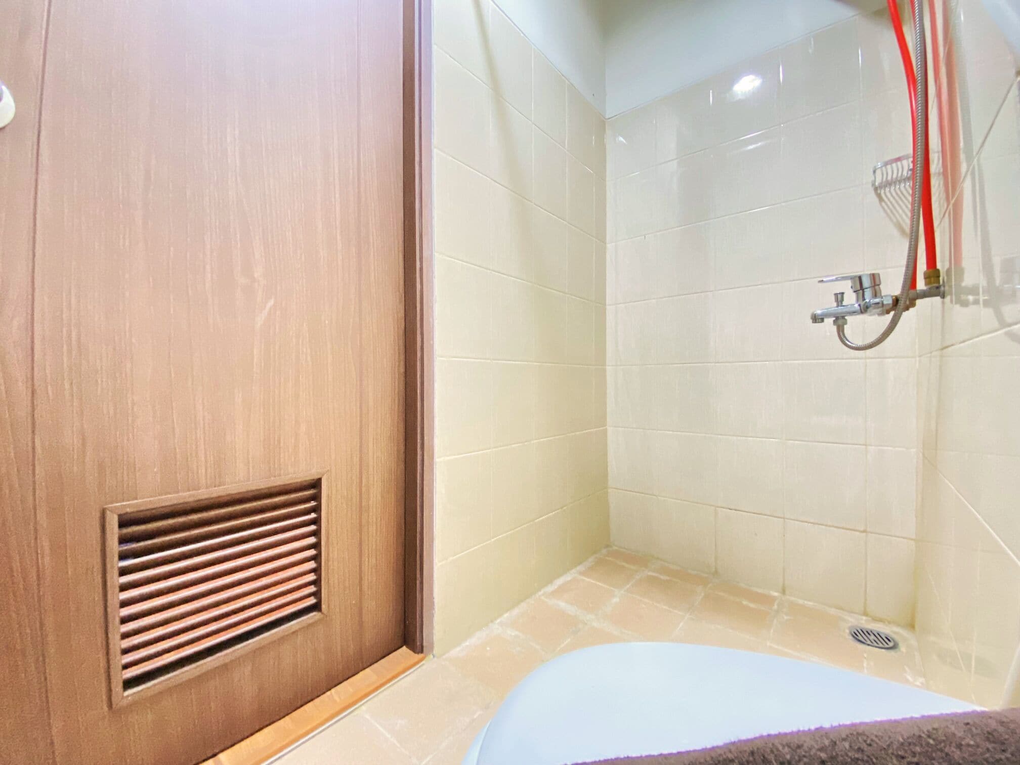 A bathroom with a wooden door, a shower with a handheld showerhead, and a bathtub.