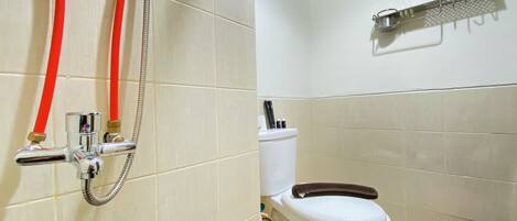 A bathroom with a toilet, a shower with red hoses, and a towel rack on the wall.