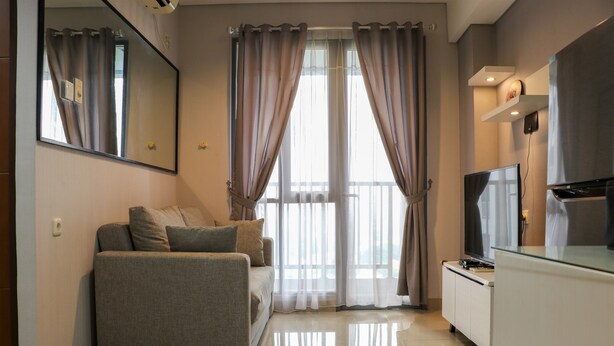 A modern living room with a sofa, a flat-screen TV, and a glass-top coffee table. - Nice And Comfy 2Br Apartment At Royal Olive Residence (Jakarta)