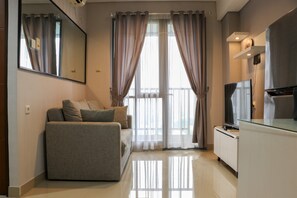 A modern living room with a sofa, a flat-screen TV, and a glass-top coffee table. - Nice And Comfy 2Br Apartment At Royal Olive Residence (Jakarta)