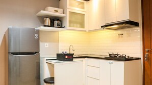 A compact kitchen with white cabinets, a stainless steel refrigerator, a gas stove, and a small countertop. - Nice And Comfy 2Br Apartment At Royal Olive Residence (Jakarta)