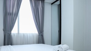 A hotel room with a bed, grey curtains, a mirror, and a window. - Nice And Comfy 2Br Apartment At Royal Olive Residence (Jakarta)