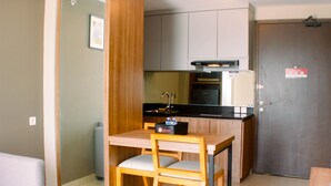 Una cocina compacta con comedor, que incluye una mesa, sillas, un refrigerador y un microondas.