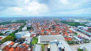 An aerial view of a densely populated urban area with a mix of residential and commercial buildings, including a prominent blue structure in the distance.