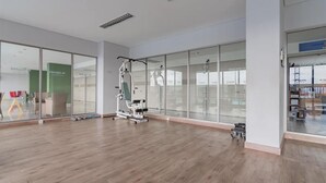A spacious room with wooden flooring, a large window, and a piece of exercise equipment.