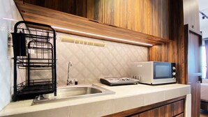 A kitchen with a stainless steel sink, a black wire rack, a microwave, and wooden cabinets.
