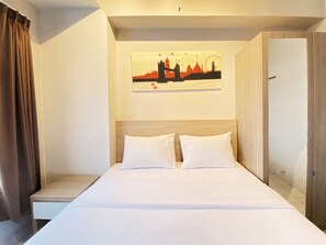 Relax in a cozy retreat with a neatly made bed, a framed cityscape, and a simple, clean design.