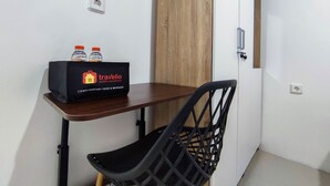 Una habitación pequeña con una mesa de madera, una silla negra y una bolsa negra con la etiqueta 'Travelio' sobre la mesa.
