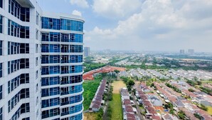 A high-rise building with multiple floors and large windows, overlooking a residential area with houses and greenery. - Stunning And Spacious 2Br Brooklyn Alam Sutera Apartment (South Tangerang)