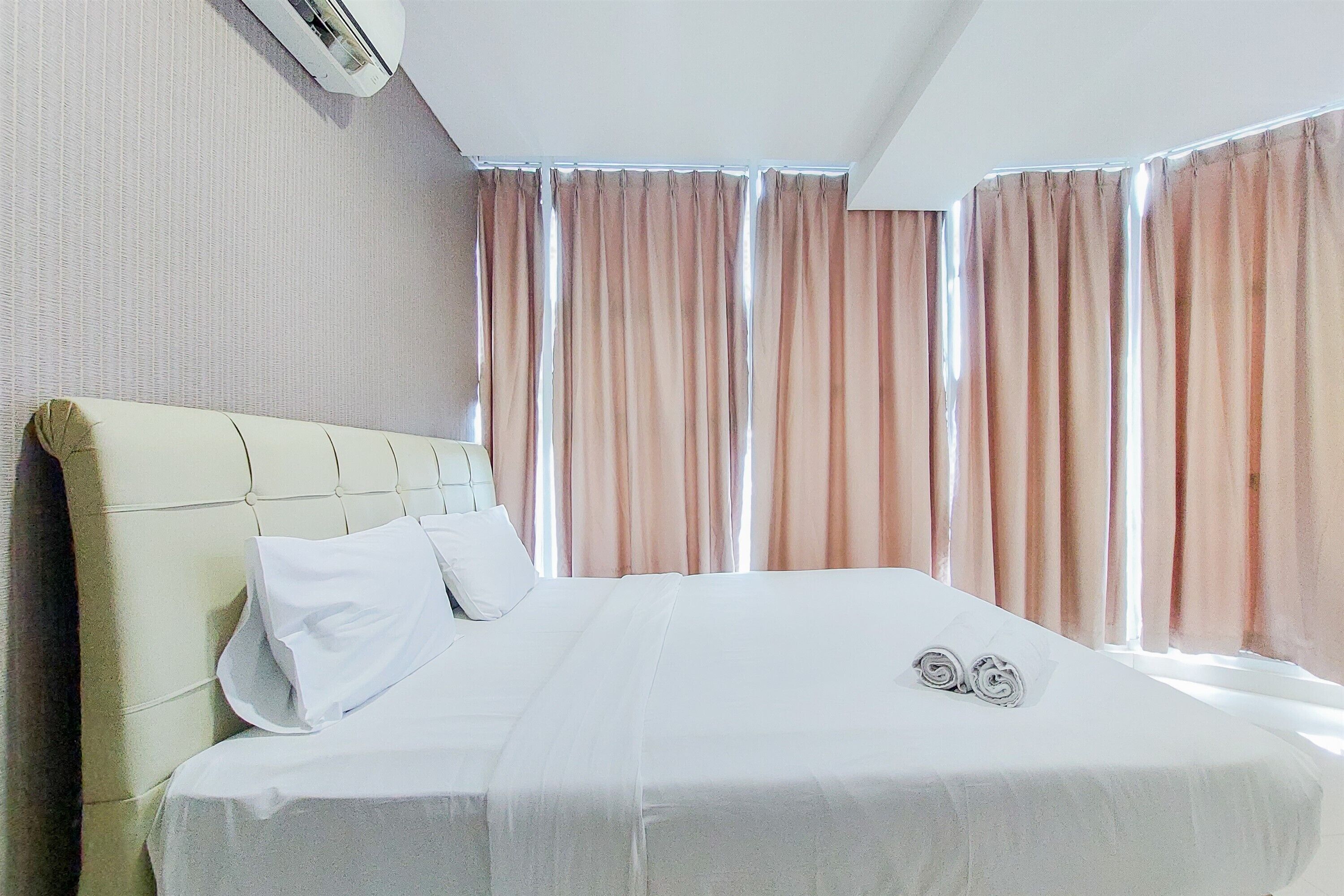 Une chambre d’hôtel avec un grand lit, une tête de lit et des rideaux.