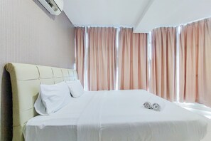 Een hotelkamer met een groot bed, een hoofdbord en gordijnen.