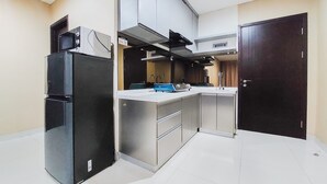 A compact kitchen with a black refrigerator, a microwave, and a stove. There is a sink and cabinets. - Stunning And Spacious 2Br Brooklyn Alam Sutera Apartment (South Tangerang)