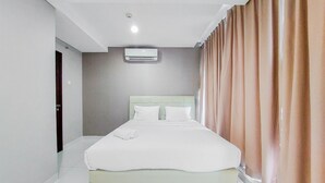 A hotel room with a bed, a ceiling-mounted air conditioner, and a door. - Stunning And Spacious 2Br Brooklyn Alam Sutera Apartment (South Tangerang)