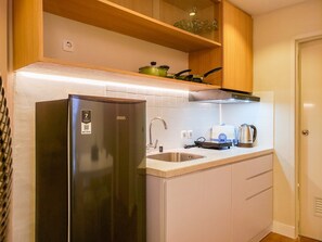 A compact kitchen with a stainless steel refrigerator, a sink, and a countertop with a toaster and kettle. - Simple And Cozy Designed 2Br Apartment At Tokyo Riverside Pik 2 (Teluknaga)