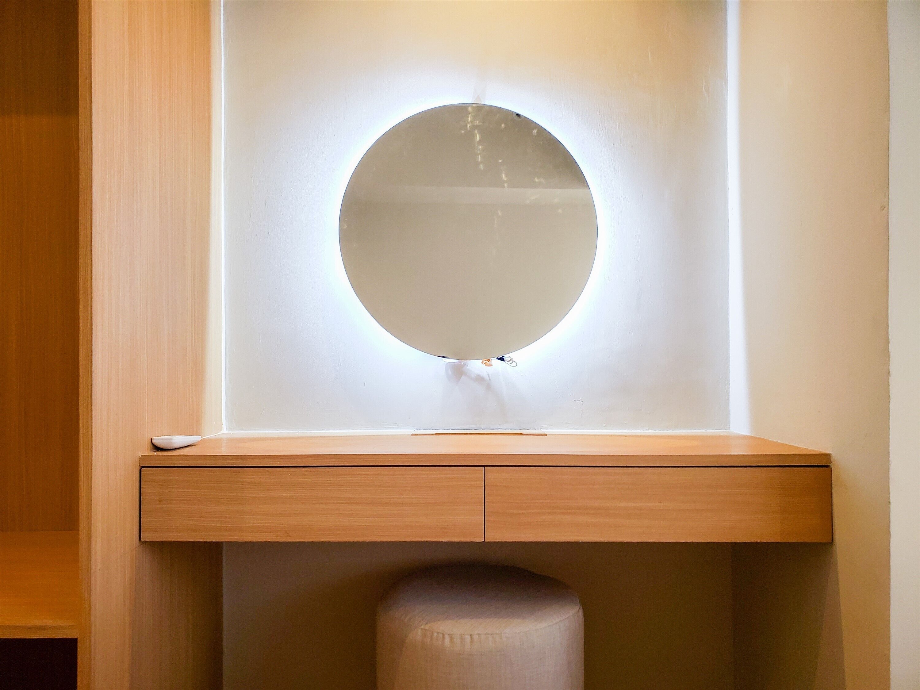 Ein Badezimmer mit einem Holzkosmetikschrank, einem runden Spiegel und einer Toilette.