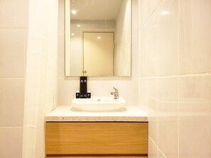 A bathroom with a white sink, a mirror above it, and a wooden cabinet below. - Simple And Cozy Designed 2Br Apartment At Tokyo Riverside Pik 2 (Teluknaga)