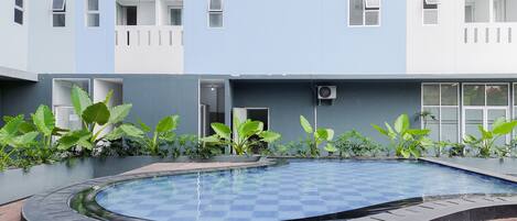 Un edificio moderno con piscina, rodeado de abundante vegetación.