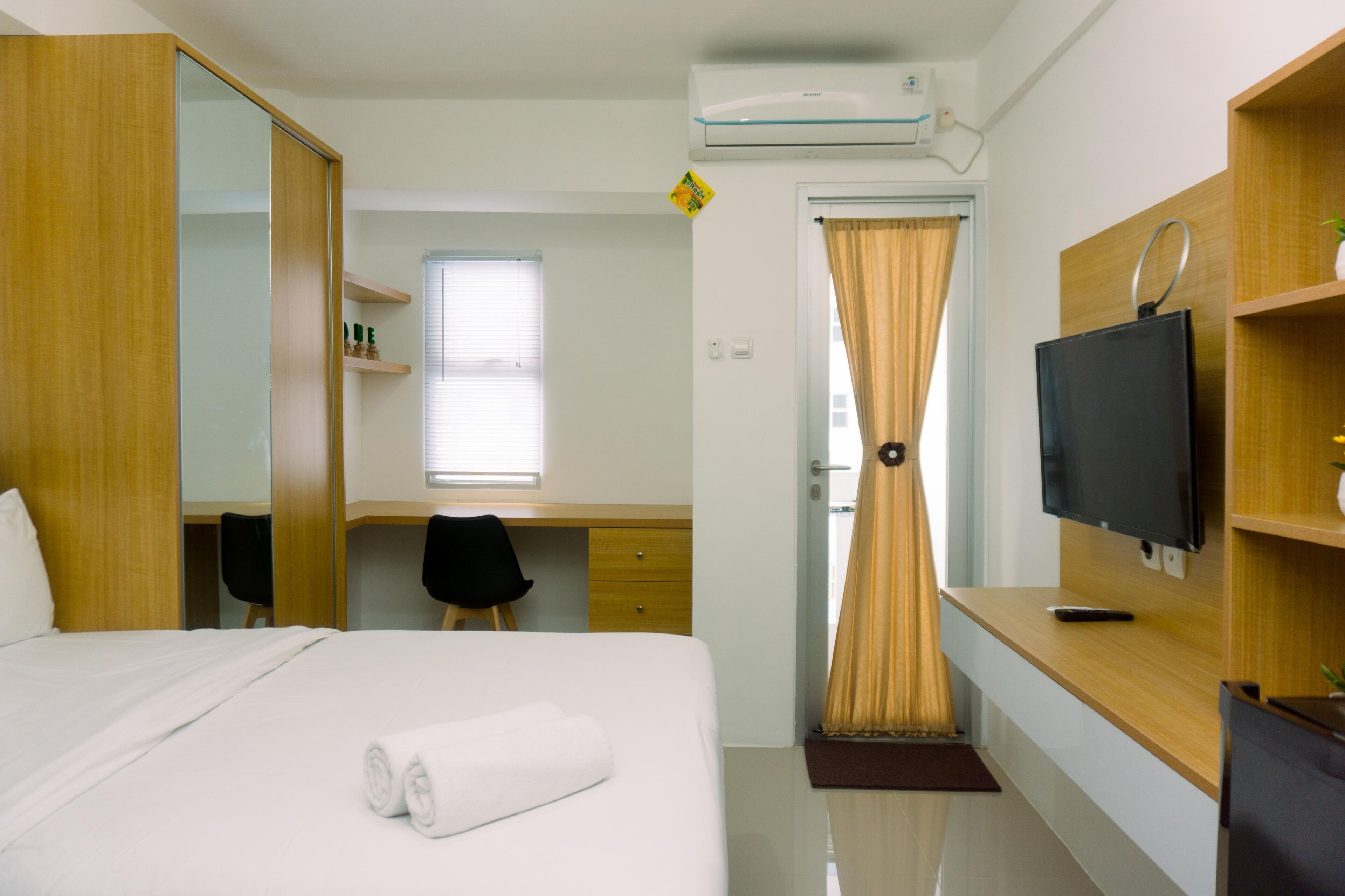 A hotel room with a bed, a desk, a television, and a wardrobe.