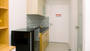 A compact kitchen with a black refrigerator, wooden cabinets, and a tiled backsplash. - Cozy Studio At Urbantown Serpong Apartment (South Tangerang)