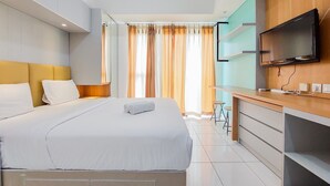 Moderni hotellihuone, jossa on suuri sänky, työpöytä ja litteänäyttöinen televisio sekä suuret ikkunat, joista avautuu näkymä kaupunkiin.