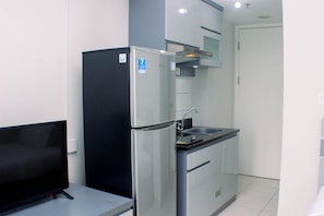 Een kleine keuken met een koelkast, een wastafel en een aanrecht.