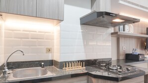 Una cocina moderna con un lavamanos de acero inoxidable, armarios de madera, una estufa a gas y una campana extractora.