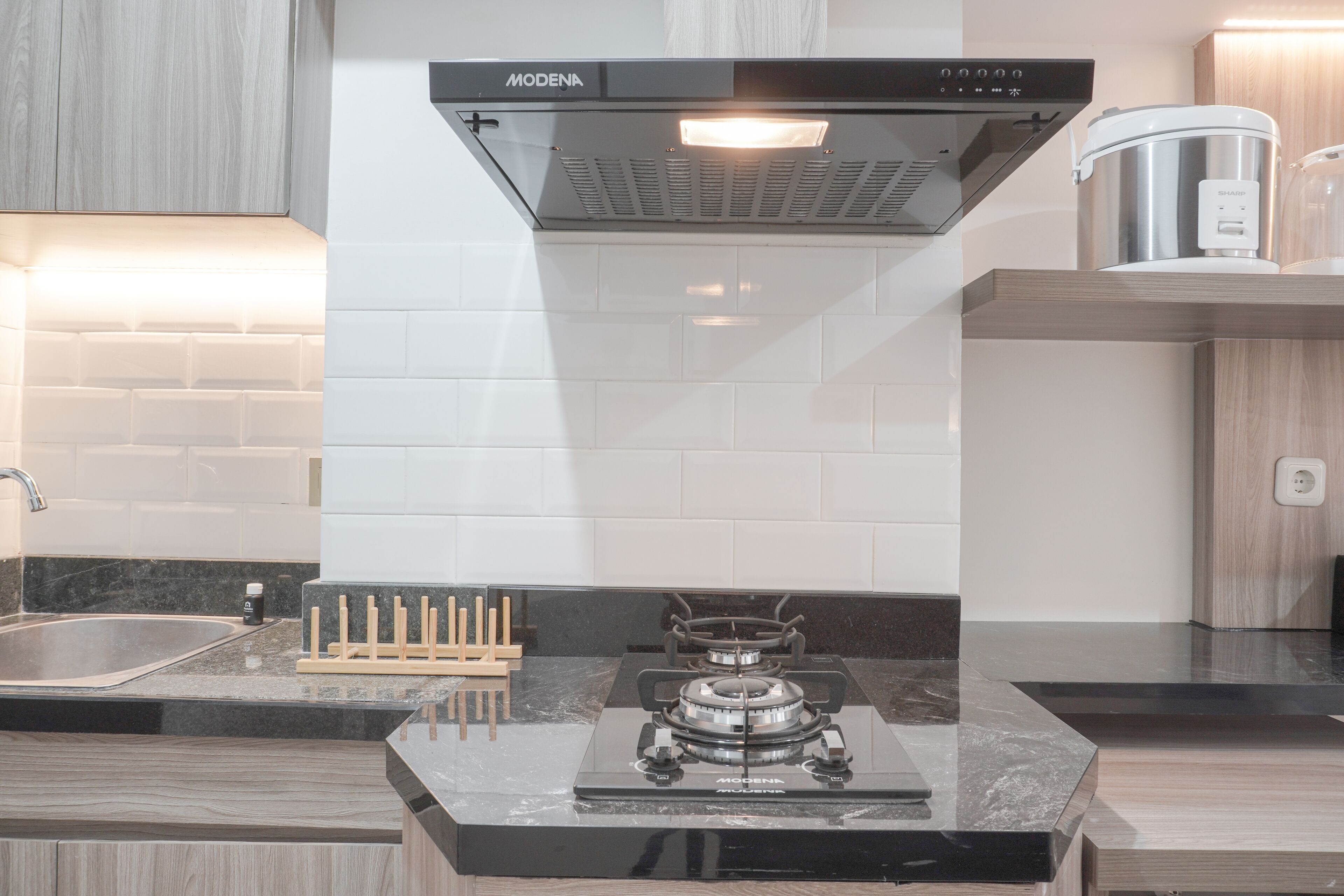 A modern kitchen with a black stove, white tiled backsplash, and wooden cabinets.