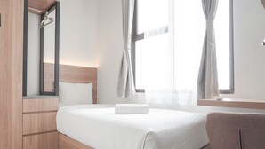 Una habitación de hotel moderna con un cabecero de madera, un espejo grande y una ventana con cortinas.