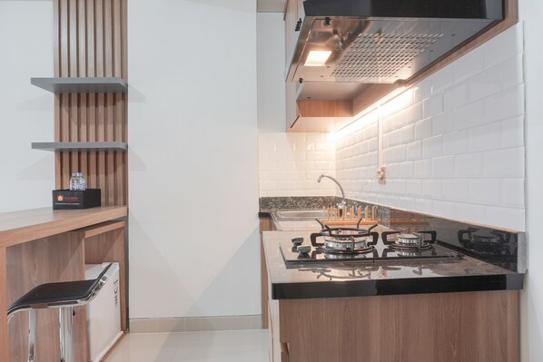 Una cocina moderna con estufa a gas, horno empotrado, campana extractora de acero inoxidable y encimera de madera.