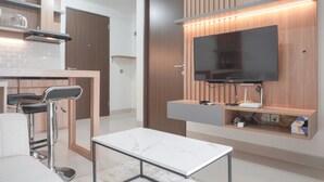Una cocina moderna con televisión integrada, un taburete de bar y encimera de mármol.