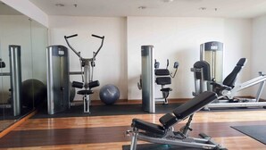 Une salle de sport équipée de matériel d’exercice, dotée d’un mur avec des miroirs et d’un plancher en bois.