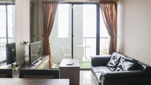 Un salon comprenant un téléviseur, un canapé, une table basse et une porte-fenêtre coulissante donnant sur un balcon.