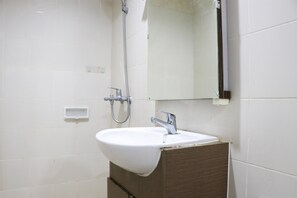 Un baño con un lavamanos blanco, un espejo y una ducha.