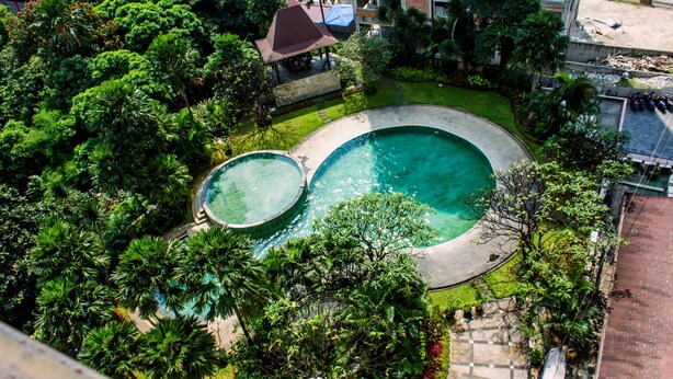 Vue aérienne d’un complexe hôtelier doté de deux piscines, entouré d’une végétation luxuriante et agrémenté d’un petit pavillon.