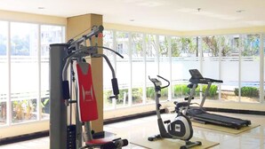 Un gimnasio con máquinas de cardio y equipo de pesas, amplias ventanas y vistas al exterior.