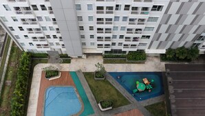 A high-rise residential building with multiple balconies, a swimming pool, and landscaped areas. - Well Furnished Studio At Citra Living Apartment By Tarvelio (Jakarta)