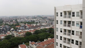 A high-rise building with multiple balconies and a view of a cityscape. - Well Furnished Studio At Citra Living Apartment By Tarvelio (Jakarta)