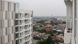 A high-rise building with multiple balconies and a view of a densely populated cityscape. - Well Furnished Studio At Citra Living Apartment By Tarvelio (Jakarta)