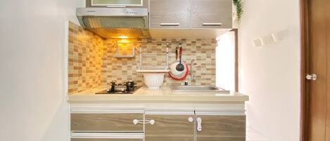 Una cocina compacta con estufa a gas, un lavamanos y armarios de madera.