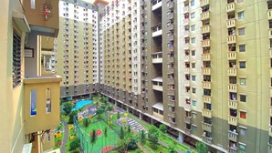 A high-rise residential building with multiple balconies, a rooftop pool, and a landscaped courtyard with a basketball court. - Fancy Designed 2Br At Gateway Ahmad Yani Cicadas Apartment (Bandung)