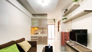 A modern living room with a brown sofa, a black coffee table, and a TV on a wooden stand. - Fancy Designed 2Br At Gateway Ahmad Yani Cicadas Apartment (Bandung)