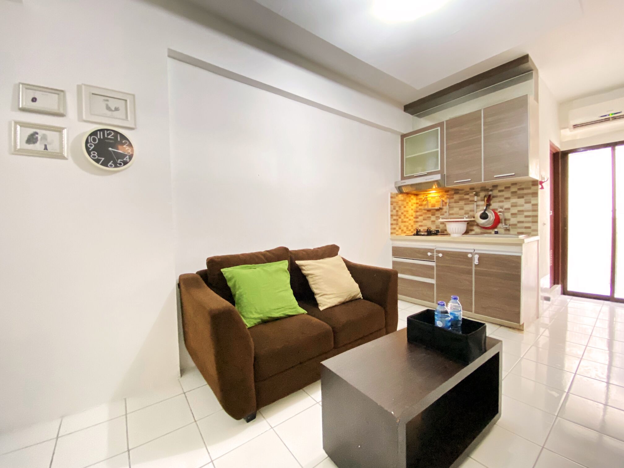 A modern living room with a brown sofa, a black coffee table, and a kitchen in the background.