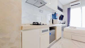 A modern hotel room with a kitchenette, a bed, a TV, and a large window with curtains.