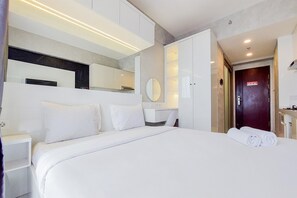 A modern hotel room with a large bed, a bedside table, a mirror, and a wardrobe.
