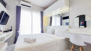 A modern hotel room with a large bed, a desk with a chair, a TV, and a bathroom mirror.